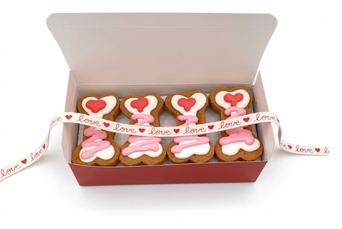 Box of bone shaped cookies with icing and heart decorations, tied with a festive ribbon.